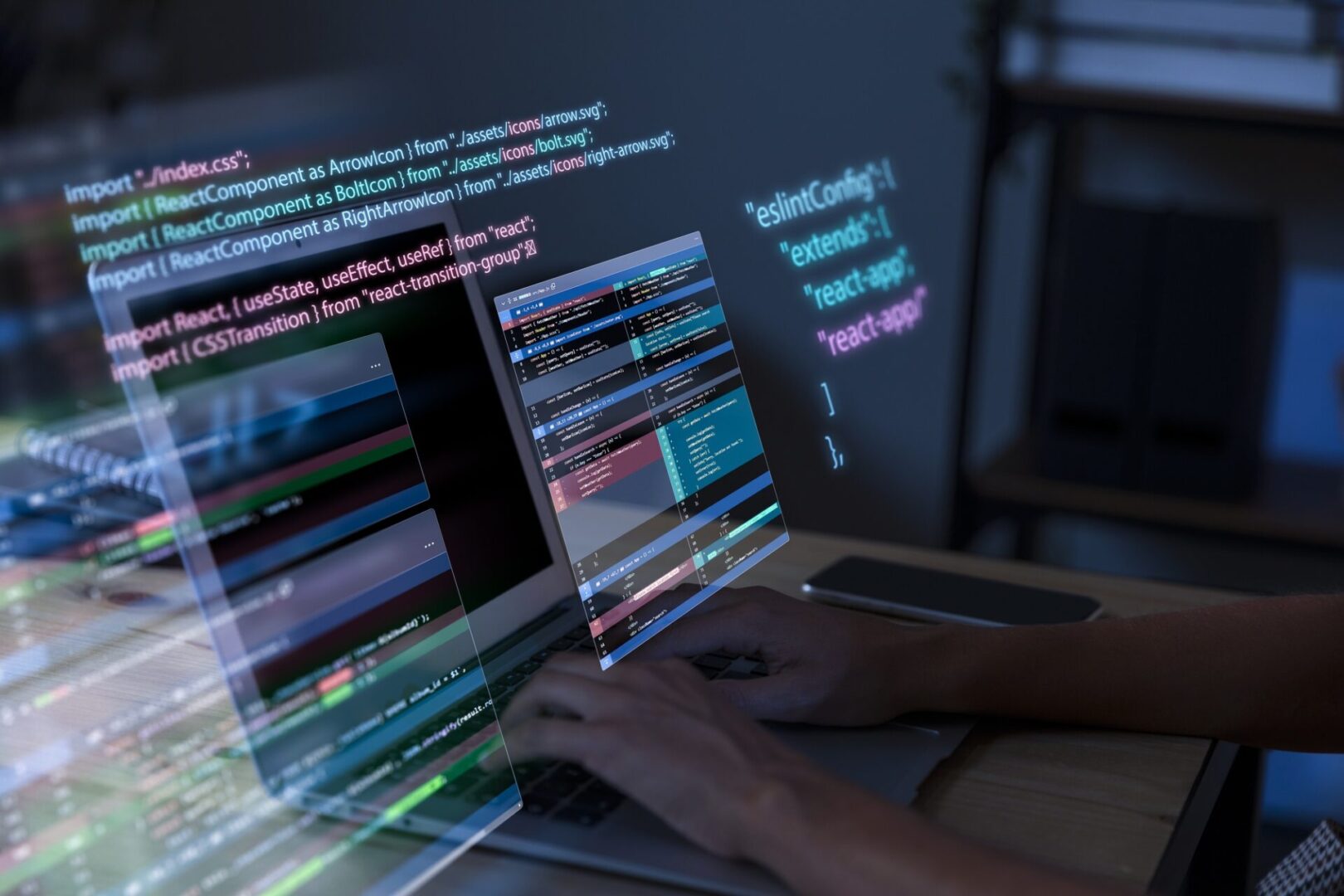 Close-up of hands typing on a laptop in a dim workspace while translucent, neon-glowing panels of React JavaScript code and project task boards hover above the screen, visually symbolizing modern software development.