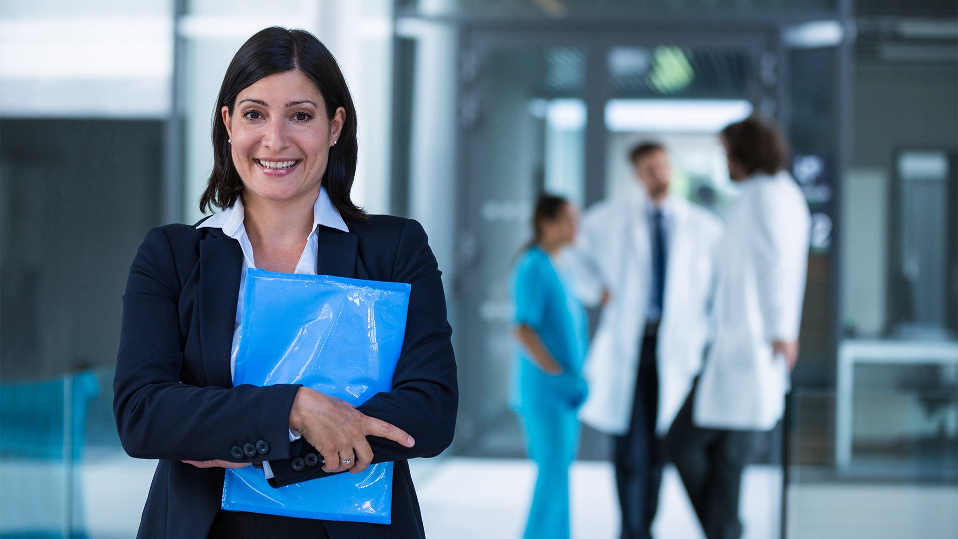 A man and woman smile and clap while proudly holding up a piece of paper.